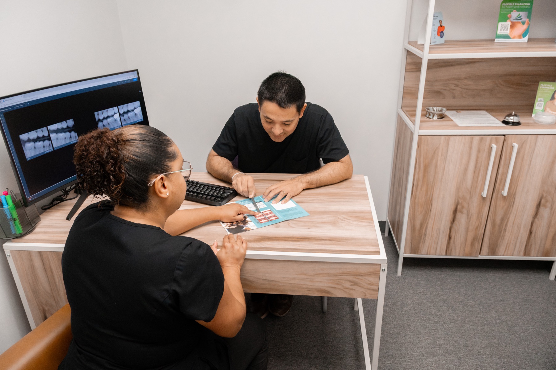 A Gardens team member reviewing a treatment plan and X-rays with a patient at the consultation desk
