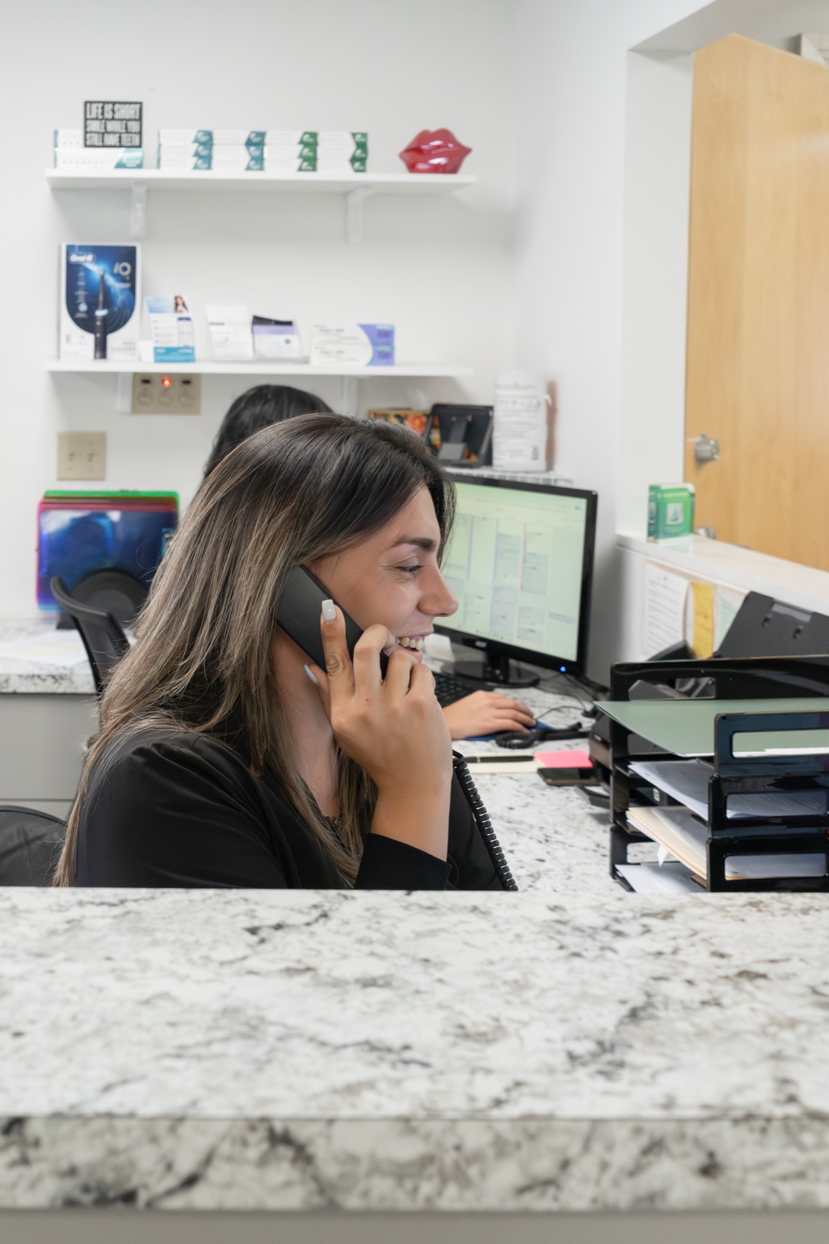 A Gardens Implant and Cosmetic Dentistry front desk team member answering the phone at the Palm Beach Gardens office