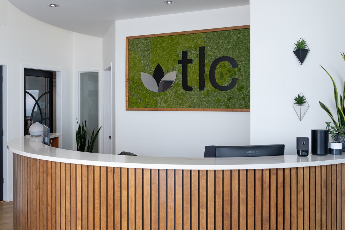 The reception desk at TLC Family Dental Centre in Leduc, with the TLC logo on the wall behind it